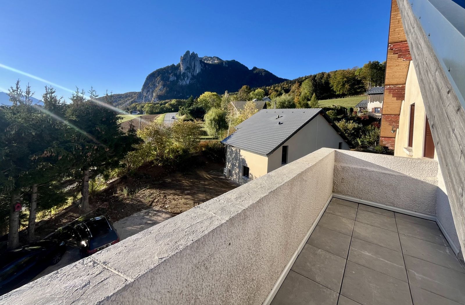 Le balcon carrelé et son muret, avec vue sur les Trois Pucelles sous le soleil