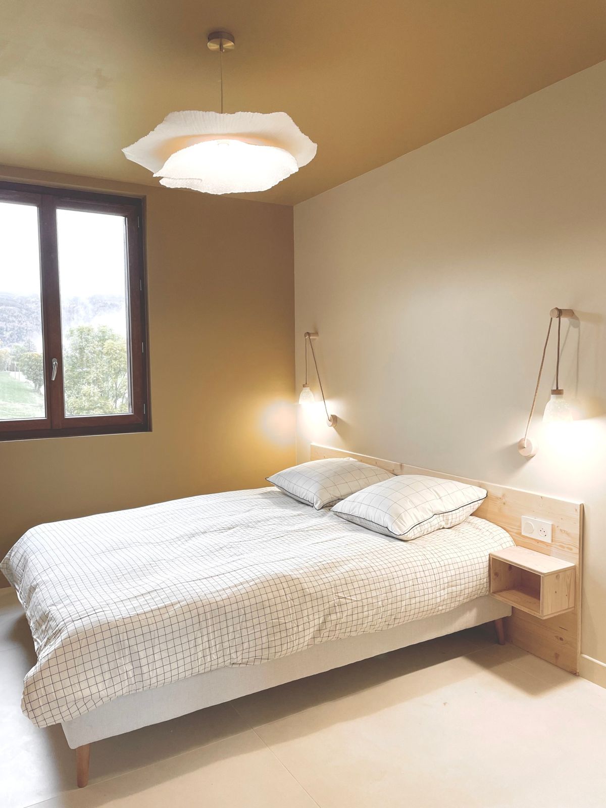 La chambre ocre : lit double, suspension en papier et fenêtre ouverte sur la nature